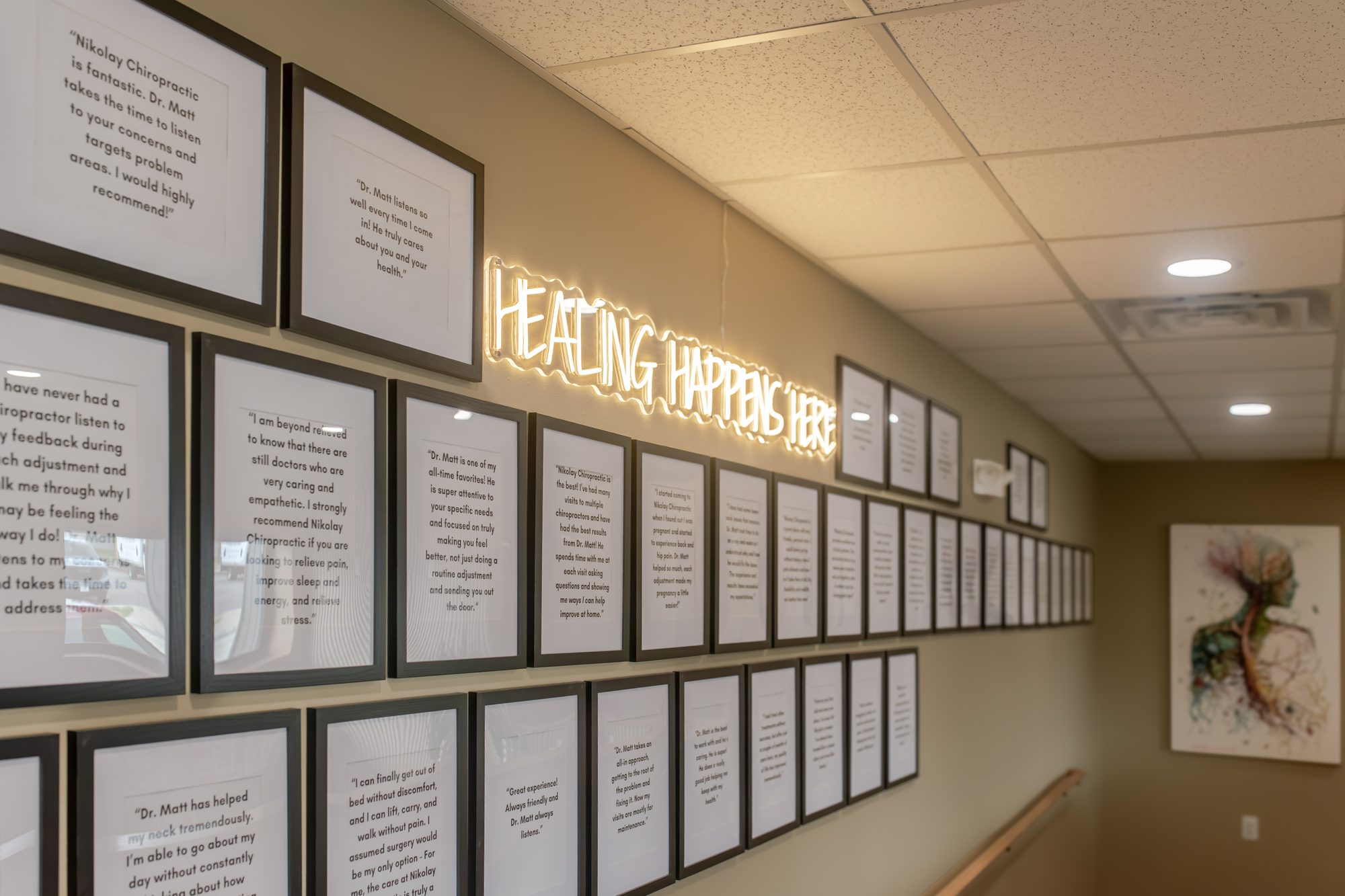 The review wall inside the clinic, with a neon sign reading Healing Happens Here